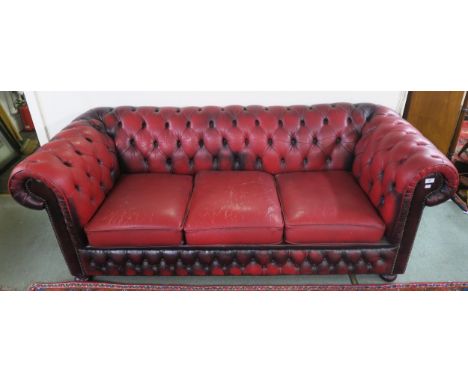 A 20th century oxblood leather upholstered button back chesterfield style three seater club sofa on bun feet, 74cm high x 197