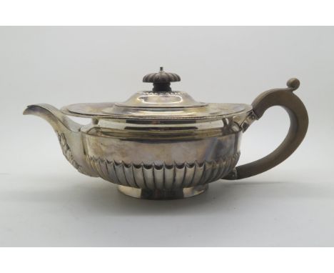 An Edwardian silver teapot, of squat circular form, the body half fluted, with acanthus leaf decoration to the spout, with wo