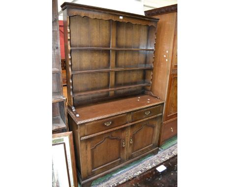 An oak dresser, stepped cornice, three shelves, moulded top, two short drawers over two panel door cupboard to nase.