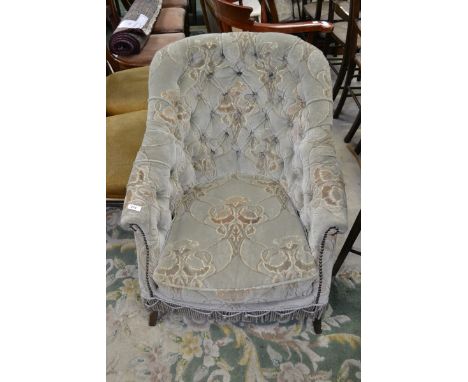 An Edwardian button back, scroll armed fireside chair.