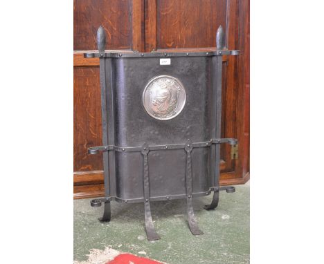 An Arts and Crafts wrought iron fireguard with armorial crest.