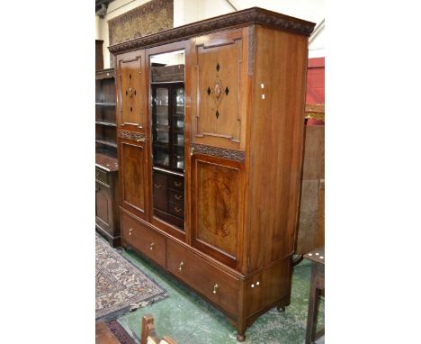 A mahogany triple wardrobe, cornice carved with scrolling swags, mirrored panel flanked by doors each panelled with cabachon 