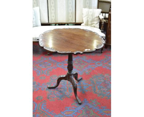 A Victorian mahogany tilt-top pedestal table, the top carved to the edge with scrolling floral motifs, tripod base, cabriole 