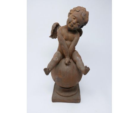 A cast iron cherub sitting on a globe raised on socle base, H.40cm 