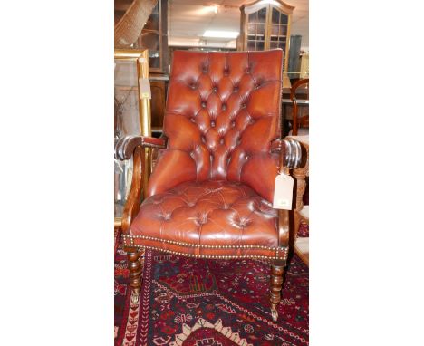 A Victorian mahogany library armchair, with stud bound red leather button back upholstery, raised on turned legs and castors 