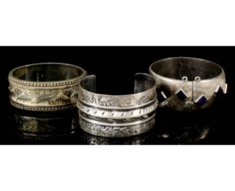 A Mexican "Taxco" sterling silver stiff bangle of textured form, set with twelve rectangular cut purple stones, and two other