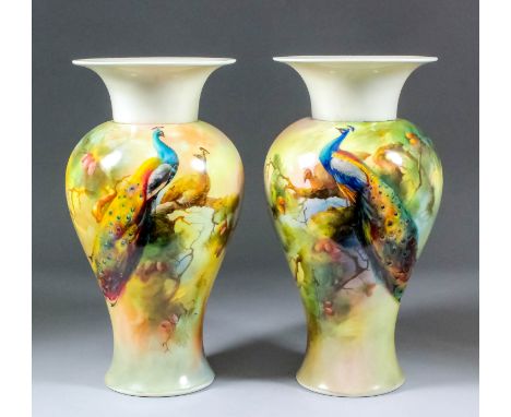 A pair of late 19th Century Royal Worcester bone china vases of baluster form enamelled in colours with peacocks amongst bran