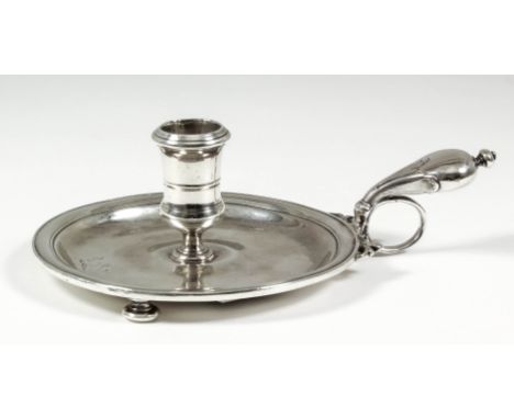 A good Queen Anne silver circular chamber candlestick with moulded rim and sconce and bulbous leaf capped handle, on three bu