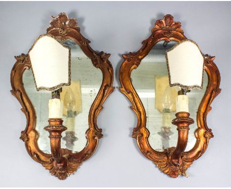 A pair of Italian gilt wood framed single branch wall lights with shaped and moulded back plates inset with mirror panels, wi