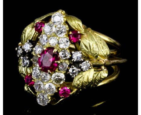 A gold coloured metal mounted ruby and diamond ovoid cluster ring, set with central oval ruby, sixteen small diamonds flanked