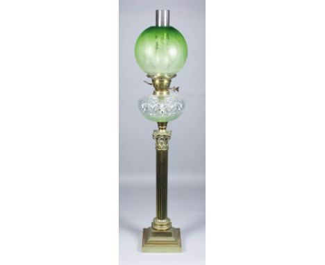 A late Victorian oil lamp with etched green tinted glass spherical shade, slice and fan cut reservoir and on reeded brass col