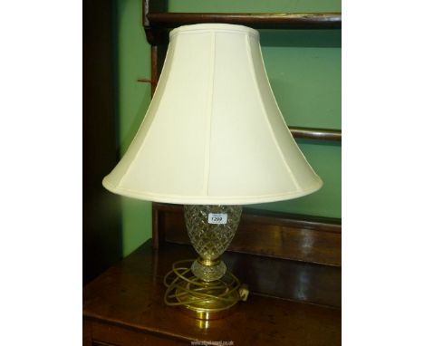An electric cut glass and brass table lamp with cream shade.