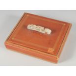 A CHINESE SQUARE FORM LIDDED BOX WITH MOUNTED CARVED JADE BELT HOOK HANDLE, the lid opening to