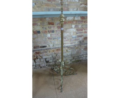 An adjustable brass standard lamp on a scroll tripod base