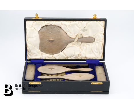 A silk lined box containing a dressing table vanity set, comprising mirror, two hairbrushes and two clothes brushes and a com