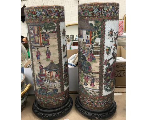 A pair of modern Chinese famille-rose circular stick stands, 61 cm high, on associated wooden stands