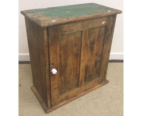 A pine cupboard, the plain top above a single panelled door opening to reveal a shelf, raised on a plinth base, 65.5 cm wide 