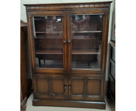 An Ercol dark oak display cabinet with 2 glazed and 2 panelled doors 