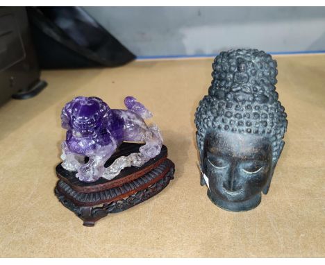 A Chinese amethyst coloured hardstone figure of dog of foe on hardwood stand (some areas damaged), a cast metal budha head