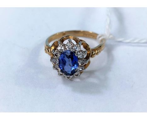 A 9 carat hallmarked gold dress ring set oval sapphire coloured stone, surrounded by clear stones, 2.5 gm.  Size K 