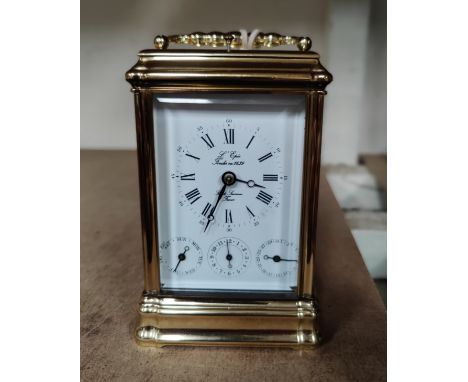 A reproduction brass carriage clock with repeating/striking movement, white enamel dial with 3 subsidiary drawers, the dial l