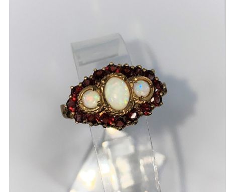 A vintage 9ct hallmarked dress ring set with 3 opals surrounded by 16 garnets size Q 5.7gms 