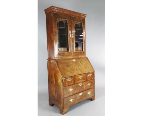 An early 18th century walnut bureau bookcase, with two glazed doors enclosing pigeonholes and drawers over a fall enclosing a