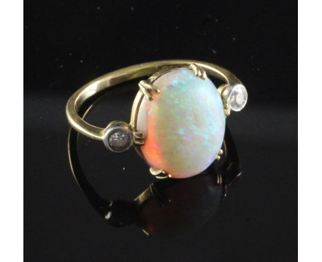 An 18ct gold, white opal and diamond ring, the central oval opal flanked by two round cut diamonds, size I.