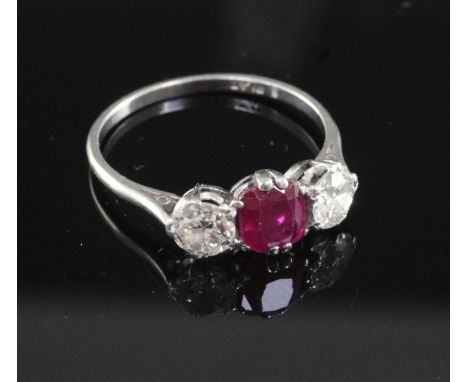 A mid 20th century platinum, ruby and diamond three stone ring, the oval cushion cut ruby flanked by two round cut diamonds, 