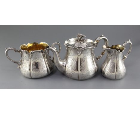 A Victorian three piece silver tea set by Henry Wilkinson & Co, of baluster form and engraved with foliate scrolls and armori