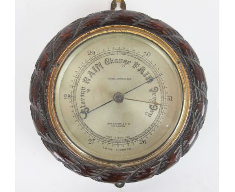 A carved oak aneroid barometer, retailed by John Baker & Co Kensington, 13cm diam; with a 1930's German walnut mantel clock, 