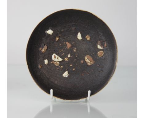 Dame Lucie Rie D.B.E (1902-1995) a stoneware saucer, glazed in manganese and scattered with white glazed stoneware shards, th