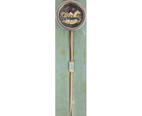 A Victorian yellow and white metal stick pin, the circular terminal decorated with a gilt metal and enamel jockey and horse, 