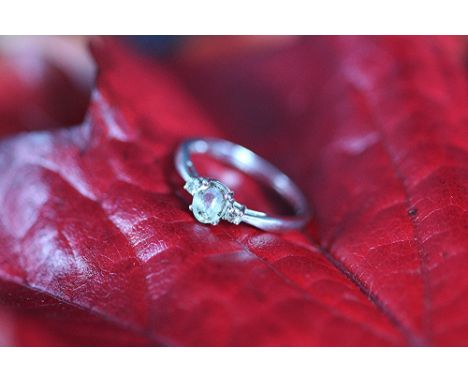 A diamond and aquamarine three stone ring, the central oval aquamarine flanked by a diamond to ether side, all set in 9ct whi