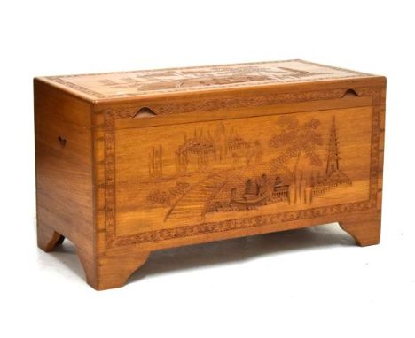 Mid 20th Century Oriental carved camphor wood trunk, the hinged flat cover decorated with figures on a bridge before pavilion
