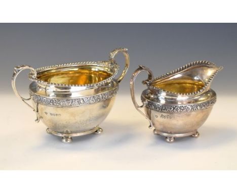 Victorian silver two handled sugar basin and matching cream jug, each having a gadrooned rim, a band of foliate decoration an