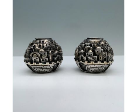 2 candle holders intricately carved with the design of the city of Jerusalem on their bodies, each with a distinctive brick g
