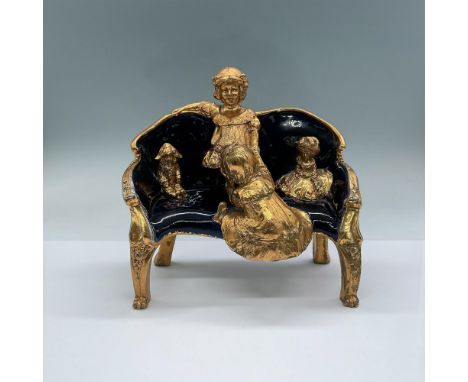 Cobalt Blue and gold detailed statuette of two girls playing on a sofa with their dolls waiting patiently. One girl is trying
