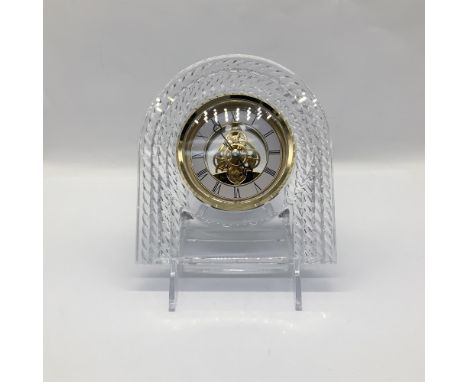 Gold-colored Roman numeral clock with inner parts showing through the dial face, enclosed in clear arched glass with a rope d