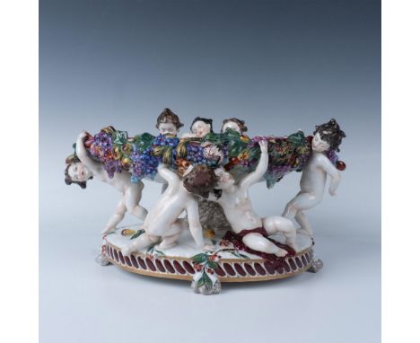 This gorgeous centerpiece dish features charming figures of putti's, beautifully hand-painted, holding up the center bowl. Th