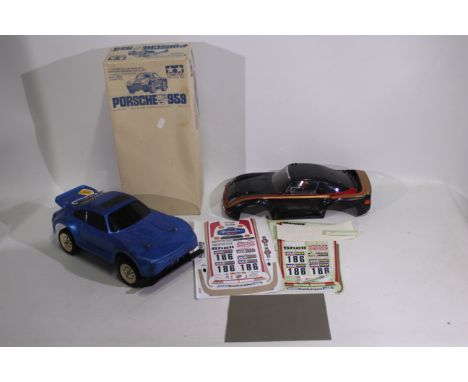 Tamiya - An unboxed vintage Tamiya 1:12 electric RC Porsche chassis with a boxed Tamiya #50306 Porsche 959 body parts set. Th