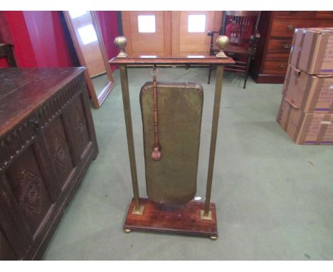 An Arts &amp; Crafts oak and brass dinner gong with sunray decoration the brass finials on bun feet and plinth base (with rin