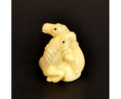 A signed carved walrus tusk Netsuke composition of two horses with black obsidian eyes, H. 3.5cm.