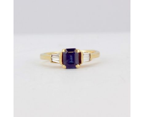 A 14ct yellow gold ring set with an emerald cut sapphire and tapered baguette cut diamond set shoulders, (R), with WGI certif