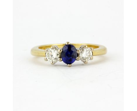 An 18ct yellow gold ring set with an oval cut sapphire and brilliant cut diamonds, (K).