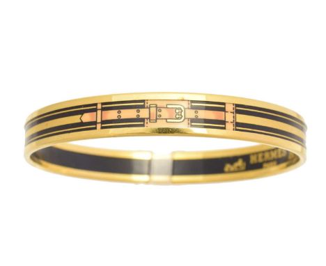 A Hermès enamel bangle bracelet, the black enamel bangle with tan and gold tone belt and buckle decoration, signed Hermès.Inn