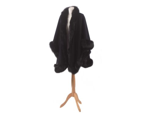 A fur tipped wool cape, the black wool cape with undulating hem and black fur trim. Condition report: Overall condition good,