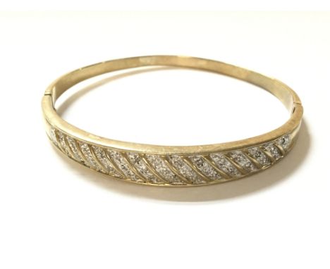 A 9ct gold bangle set with diamonds. Weight 15.2g.