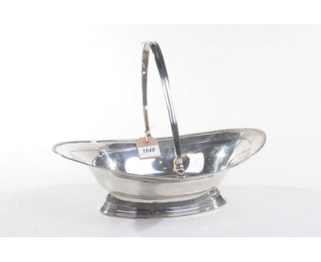 A Georgian silver swing -handled basket
Raised on a swept pierced gallery base, to an arched bowl with beaded rim and engrave