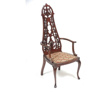 An Edwardian mahogany elbow chair
With a waisted leaf and anthemion pierced back, padded tapestry seat raised upon cabriole f